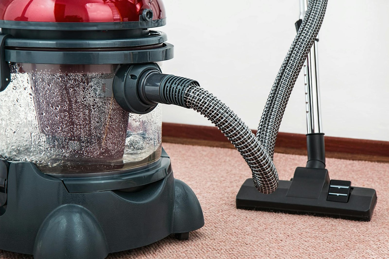 Close-up of a modern vacuum cleaner with water filtration on carpet floor indoors.